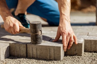 Gri beton döşeme döşeme döşeme döşeme döşeme döşeme genç adam ev avlusunda temel çakıl. Usta kaldırım taşlarını serer. Profesyonel kaldırım işçisi tarafından kaldırım taşı döşenmiş. Kaldırımları onarıyorum..
