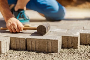 Gri beton döşeme döşeme döşeme döşeme döşeme döşeme genç adam ev avlusunda temel çakıl. Usta kaldırım taşlarını serer. Profesyonel kaldırım işçisi tarafından kaldırım taşı döşenmiş. Kaldırımları onarıyorum..