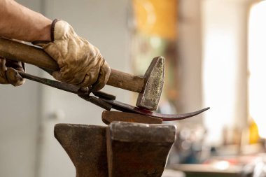 Isıtılmış metal ve örsün yakın görüntüsü. Demirhanede el yapımı metal ürünlerinin üretim sürecindeki demirci. Demirci çekiçle metal dövüyor. Metal endüstrisi, eski meslek