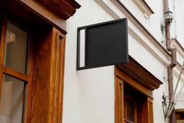Blank signboard mock up, on the facade. Copy space for your store sign or logo. Modern empty outdoor signage, mockup to add company logo. Black square store signboard on white wall