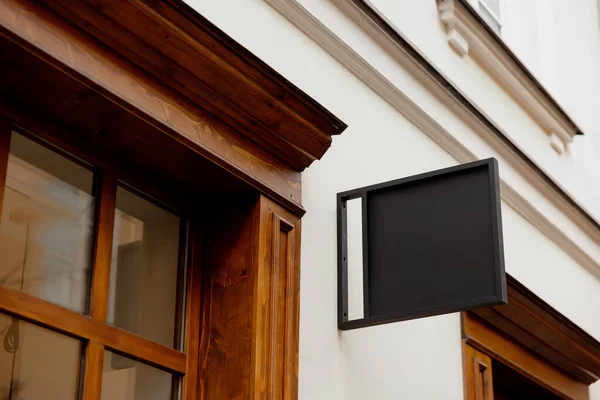 Blank signboard mock up, on the facade. Copy space for your store sign or logo. Modern empty outdoor signage, mockup to add company logo. Black square store signboard on white wall