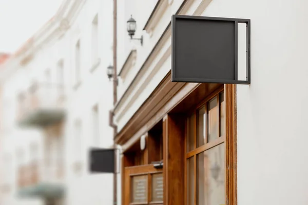 Blank signboard mock up, on the facade. Copy space for your store sign or logo. Modern empty outdoor signage, mockup to add company logo. Black square store signboard on white wall