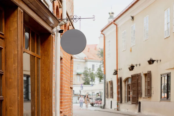 Blank signboard mock up, on the facade in old town. Copy space for your store sign or logo. Modern empty outdoor signage, mockup to add company logo. Gray round store signboard