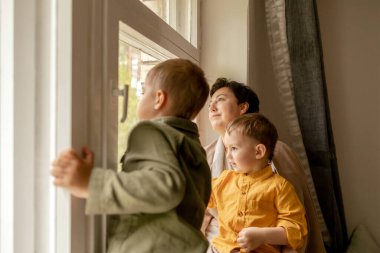 Happy grandmother and her grandsons enjoy time together. Positive middle age woman spending time with little, cute grandchildren. 50-year-old grandma with grandkids. Multi-generational family