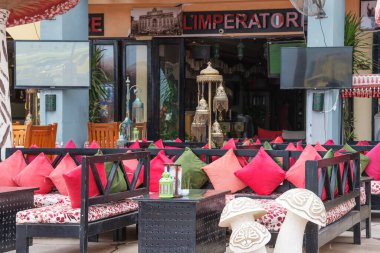 Hurgada, Mısır, 30 Ekim 2021: Hindistan tarzı açık bir sokak kafenin içi düşük kırmızı ve yeşil koltuklar, renkli yastıklar ve fenerler ve çiçeklerle süslenmiş ahşap masalar