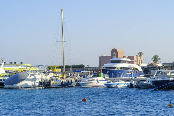 Hurghada, Egypt, November 19, 2021: View of Hurgada marina. Motorboats, ships and yachts moored at the pier in the port. Sunny day, Red Sea water is blue