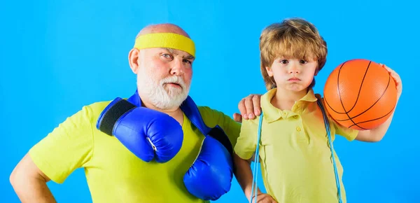 Nonno e nipote sportivi. Nipote con pallone da basket e nonno con i guanti da boxe. Sport per famiglie. — Foto Stock