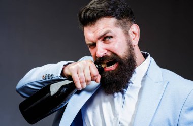 Acımasız yakışıklı adam şampanya şişesini açıyor. Dişleriyle şarap şişesini açmaya çalışan sakallı adam..