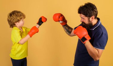 Boks eldivenli çocuk koçla antrenman yapıyor. Nakavt. Çocukluk aktivitesi. Antrenör çocuğa yumruk atmayı öğretiyor..