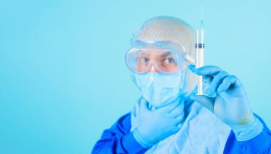 Koruyucu maskeli doktor, aşılı gözlüklü ve eldivenli şırınga. Virüse karşı aşı.