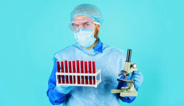 实验室工作。医生穿着防护服,戴着试管和显微镜的面具.血样技师. — 图库照片