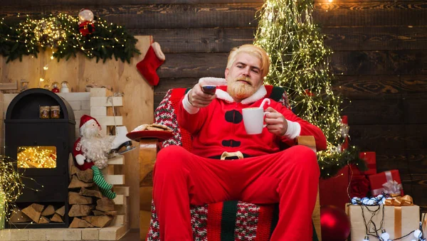 Tomten sitter i fåtöljen och dricker kaffe. God jul, då. Reklam för nytt år. — Stockfoto