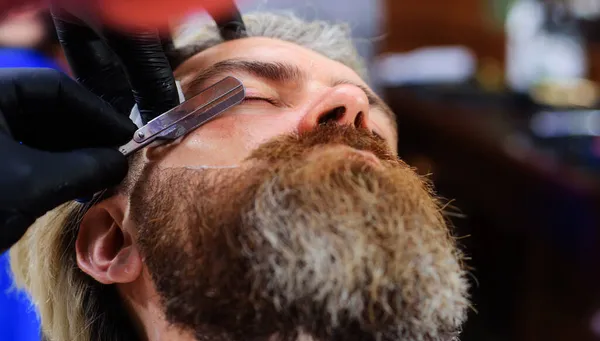 Baardverzorging. Barbershop reclame. Salon voor mannen. Kapper met scheermes. Een kapper. Mannen schoonheid procedure. — Stockfoto