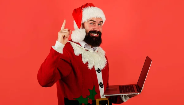 Санта Клаус с ноутбуком. Бородатый бизнесмен в костюме Санты с компьютерным указателем. Интернет-магазины. Цифровое устройство. — стоковое фото