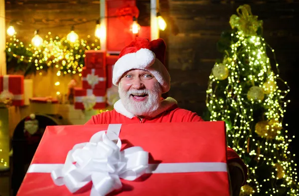 Щасливий чоловік у костюмі Санти з різдвяним подарунком. Посміхаючись над Санта Клаусом з великим подарунком. Служба доставки. — стокове фото