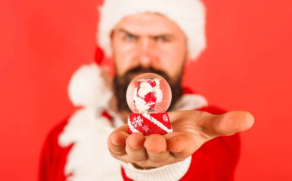 Человек в костюме Санты с маленьким снежным шаром. Рождественский снежный шар. Новогодние и рождественские украшения. Селективный фокус. — стоковое фото