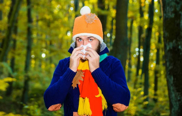 Beteg ember az őszi parkban, aki szalvétába tüsszent. A fickó köhög. Influenza, betegség, beteg, hideg. Coronavirus járvány. Férfi orrfolyás. — Stock Fotó