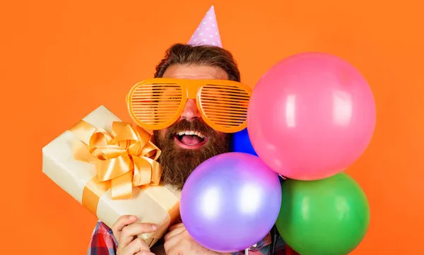 Heureux homme barbu avec boîte cadeau et ballons. Joyeux anniversaire, fêtes, fête. — Photo