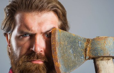 Yüzünde balta olan kendine güvenen sakallı bir adam. Ciddi bir oduncu. Keskin bıçak. Baltalı bir erkek. Yakın plan portre.