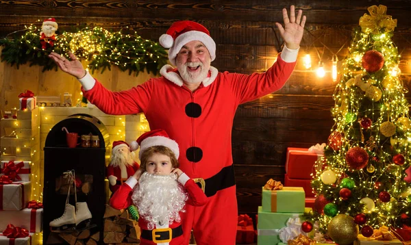 Criança com o Pai Natal em casa. Rapaz com pai vestido de Pai Natal e barba. Férias de Natal. — Fotografia de Stock