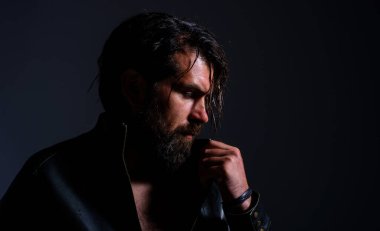 Deri ceketli, vahşi sakallı adam. Yakışıklı adamın silueti. Berber dükkanı. Sakallı dalgın adam.