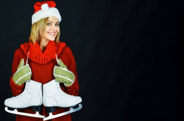 Buz pateni. Noel Baba şapkalı mutlu kadın, atkı ve buz patenli sıcak kazak. Kış sporu ve eğlence. Boşluğu kopyala.