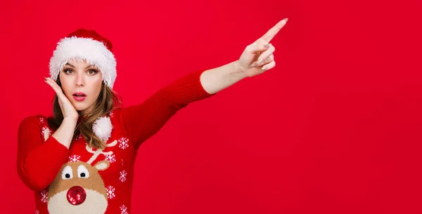 Новогодняя реклама. Удивлённая рождественская женщина указывает пальцем на пространство для копирования. Сезон продаж. Скидка. — стоковое фото