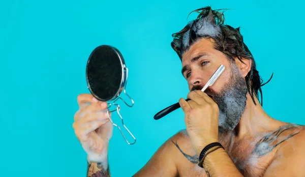 Een baard scheert zich met een scheermes in de spiegel. Baard zorg. Portret van een scheerman. Kapperszaak. — Stockfoto