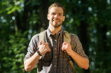 Sırt çantalı gülümseyen adam doğada tek başına seyahat ediyor. Turist kampanyası. Ormanda yürü..