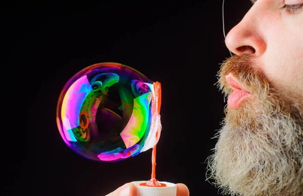Een man met baard die zeepbellen blaast. Speel met bubbels. Geluk. Goed humeur. Jeugd. Sluitingsdatum. — Stockfoto