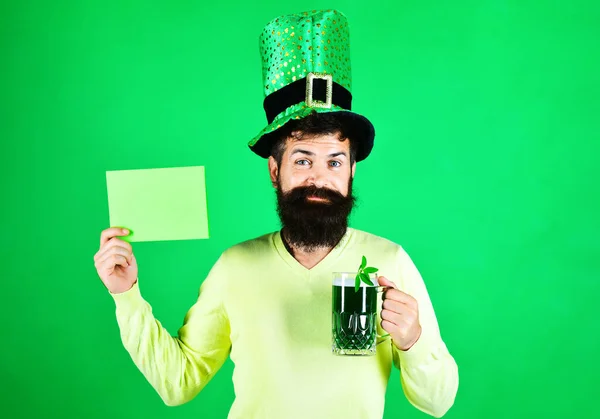 Homme barbu en chapeau avec panneau d'affichage et tasse de bière. Fête de la Journée Patricks. Trèfle à quatre feuilles. — Photo