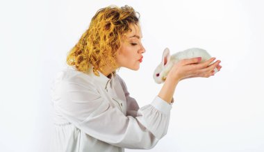 Paskalya Tavşanı. Beyaz tavşanlı mutlu kadın. Güzel kız kürklü bebek tavşanı öpüyor..