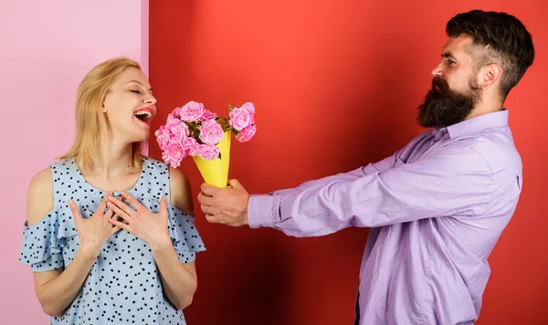 Romantic bearded man give flowers to woman. Love, relationship, dating. Couple with bouquet of roses.