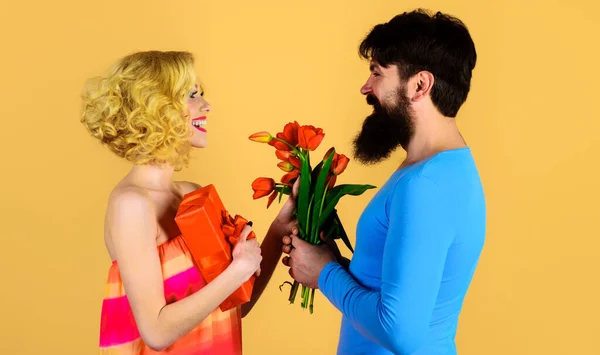 행복 한 턱수염 남자는 여자에게 꽃 과 선물을 준다. 사랑, 관계. 튤립 꽃다발을 가진 부부. — 스톡 사진