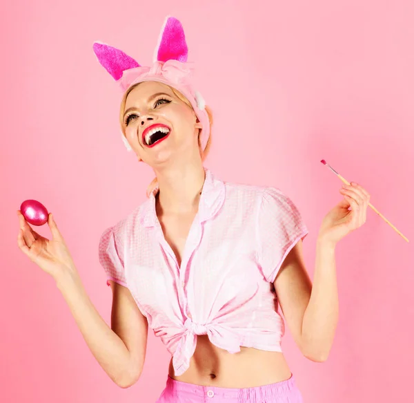 Ostersonntag. Glückliche Frau beim Bemalen von Ostereiern. Bunny girl mit Pinsel und rosa Ei. — Stockfoto