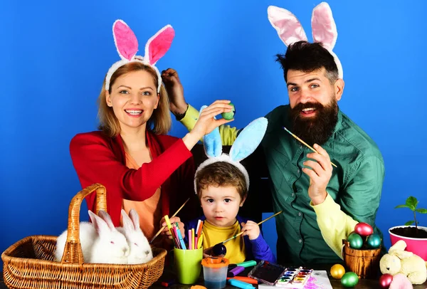 ウサギの家族は卵を描く。イースターの準備をするウサギの耳の中の母、父と息子. — ストック写真