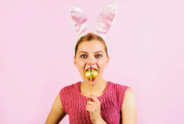 イースターエッグのアイデア。卵狩り。口の中に卵を描いたウサギの耳の女性。春休み. — ストック写真