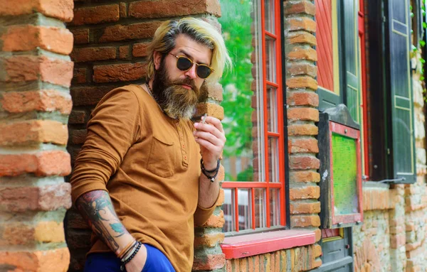 Smyslný vousatý muž Kouřící cigaretu. Stylový hipster ve slunečních brýlích kouří cigaretu. Tabák. — Stock fotografie