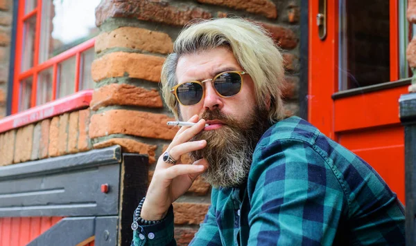 タバコを屋外でスタイリッシュな男。サングラスの喫煙タバコのひげを生やしたヒップスター。閉鎖. — ストック写真