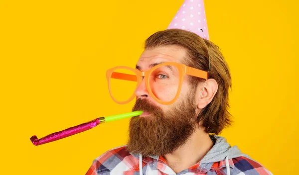 Partyzeit. Feiertage und Feiern. Bärtiger Mann mit Geburtstagskappe und großer Brille mit Krachmacher. — Stockfoto