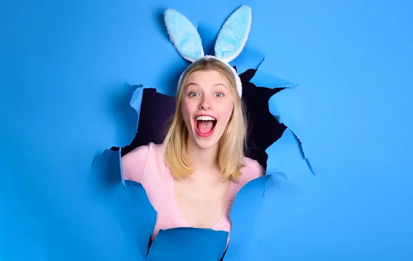 Joyeuse fête de Pâques. Femme souriante aux oreilles de lapin regardant à travers un trou de papier. Lapin fille en vacances. — Photo