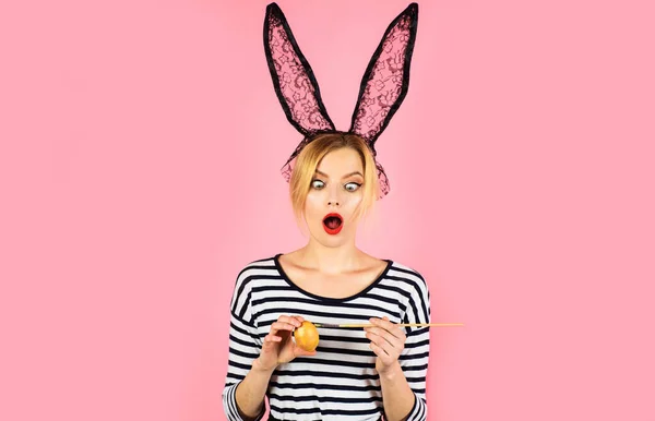 Пасхальный день. Удивлённая женщина рисует яйцо. Девочка-кролик в кроличьих ушах готовится к празднику. — стоковое фото
