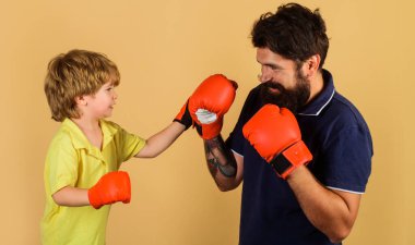Baba oğul boks antrenmanı sırasında. Eldivenli çocuk boksör koçla yumruk pratiği yapıyor..