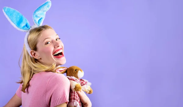 Пасхальный день. Счастливая Девочка с кроличьей игрушкой. Улыбающаяся женщина в кроличьи уши с плюшевым зайцем. — стоковое фото