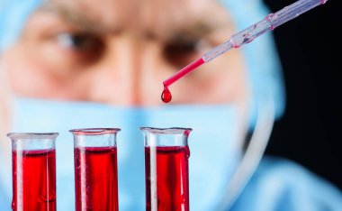 Kan örneğiyle laboratuvar teknisyeni araştırma yapıyor. Doktor ya da araştırmacı test tüpleriyle.