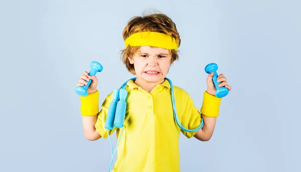 Kleiner Junge in Sportkleidung mit Springseil und Kurzhanteln. Fitnesskind. Aktivität in der Kindheit. Sportliches Kind. — Stockfoto