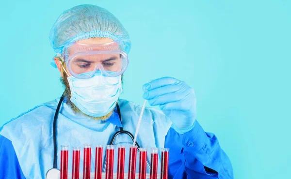 医生在实验室里检查血样。身穿个人防护服和戴面具的男性研究人员. — 图库照片