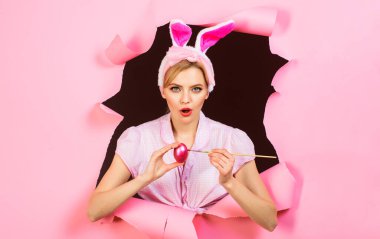 Paskalya tavşanı kadın yumurta boyuyor. Pembe yumurtası ve boya fırçası olan seksi tavşan kız. Satılık. İndirim.