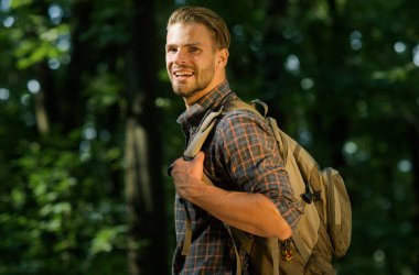 Ormanda gezen sırt çantalı mutlu bir erkek gezgin. Turizm, seyahat, macera, sağlıklı yaşam tarzı.