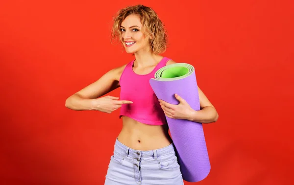 Chica deportiva mostrando el dedo en la esterilla de yoga. Entrenador deportivo instructor mujer en ropa deportiva. — Foto de Stock